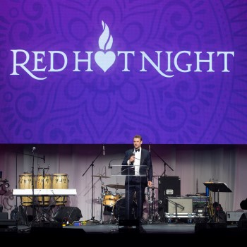 Man on stage with microphone and the words "Red Hot Night" above him.