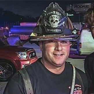 Ryan Koehler smiling and wearing his firefighter's hat.
