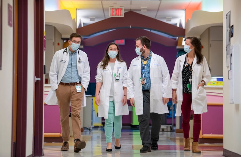 Four physicians in white coats walk through the hallway at Children's Mercy Kansas City.
