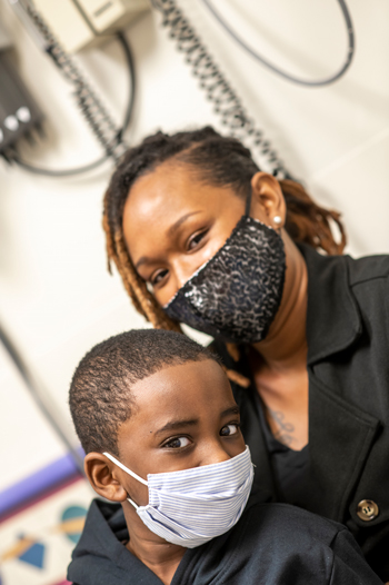 Children's Mercy patient, Chase, with his mother. Both are wearing a face mask and looking at the camera.