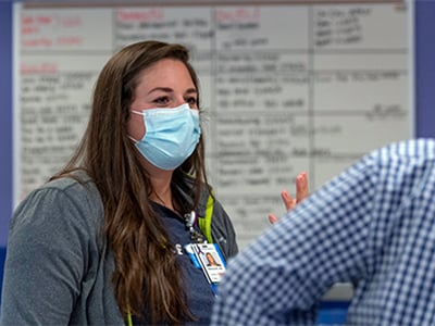 Shauna during rounds at Children's Mercy. She has a face mask on and talking with Dr. Gamis who is out of frame.