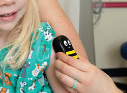 A Buzzy® bee being  applied to a child's arm.