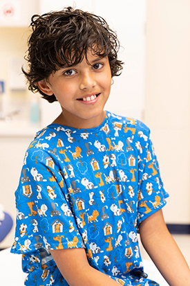 Boy in hospital gown smiling.