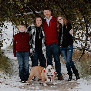 Jess Angelo standing and smiling outside with her family.
