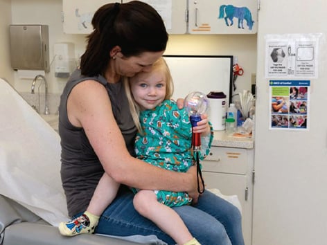 Mother holding a child on her lap in a CM hospital room.