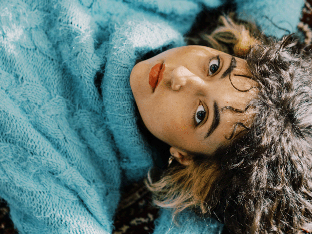Patient with blue knitted turtle neck sweater laying on the ground. 