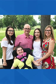 Five members of the Gallagher family smiluing while outdoors.