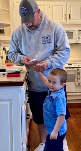 Ryan Koehler in his home kitchen testing his son's insulin level. 