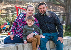 Tripp Chase smiling and sitting outside of Children's Mercy with his mother and father. 