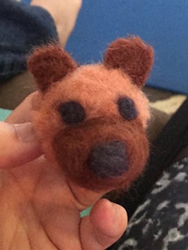 Austin's hand holding a felted bear head.