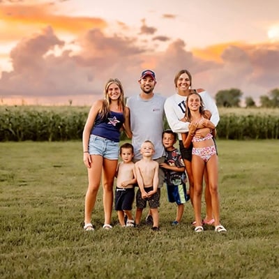 A family of seven poses together in an outdoor area.