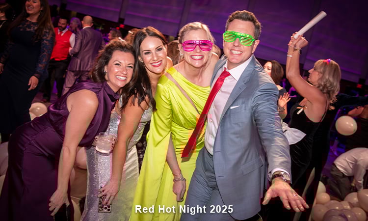 Four people in eveningwear are smiling at the camera. Two have on fun, neon-colored eyeglasses. WOrds read: Dream Big Day 2024.