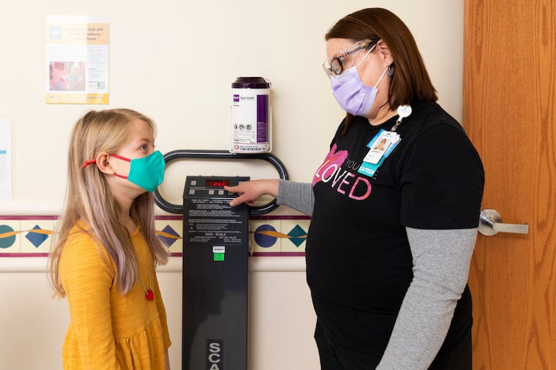 A Children's Mercy nurse shows a female child a scale..