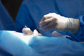 Close-up of Dr. St. Peter's gloved hands performing surgery.