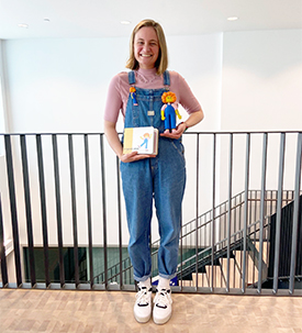 Leah smiling and holding the prototype of her children's book and medical doll for kids.