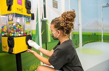 Girl with bandaged hand picking a prize at the Burn Clinic's treasure tower.