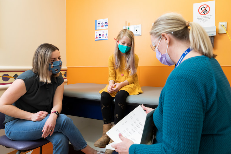 A genetic counselor talks with a patient and a parent at the Children's Mercy Genetics Clinic.