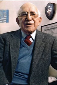 Dr. Sidney Pakula in an office with awards on the wall behind him.