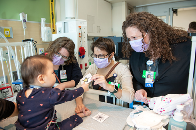 HPM Fellowship Faculty working with a patient in their crib at Children's Mercy.