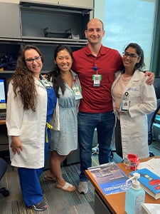 Four GI fellows smiling in an office environment with arms around each other