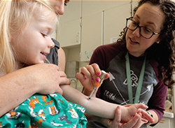 A J-Tip being used to apply numbing medication on a child's arm.