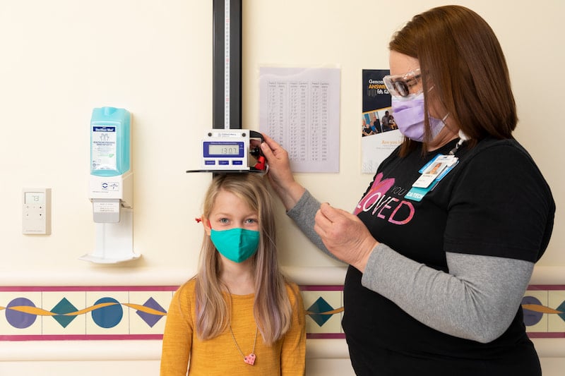 A Children's Mercy nurse measures the height of a female patient.