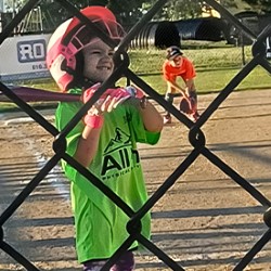 Marissa Ebbing on a baseball field, wearing a protective helmet and holding a bat.