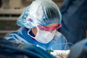Kathryn Keeler, MD, performs surgery while wearing a mask, head covering and eye protection.