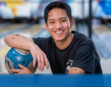 Jacob smiling in a bowling alley.