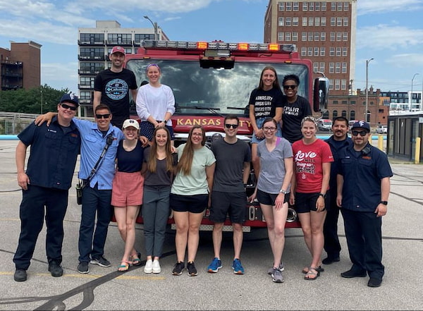 Several people stand together outside in front of a Kansas City fire truck