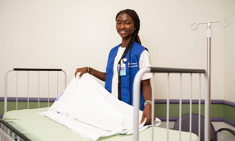 Children's Mercy college student volunteer folding a blanket at the hospital.