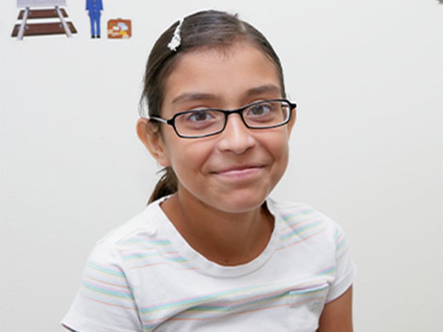 Pre-teen girl with glasses smiling.