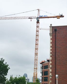 Building crane with the words "LOVE WILL." in blue at the top of it.