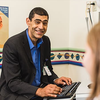 Image of Dr. Abdelmoity in clinic seated in front of computer monitor talking to a patient at Children's Mercy.