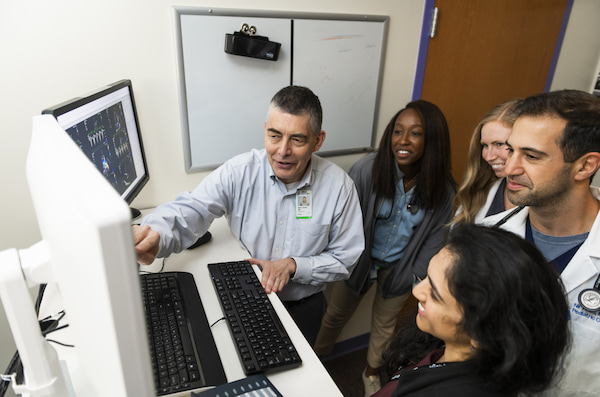 Five clinicians look together at a computer monitor