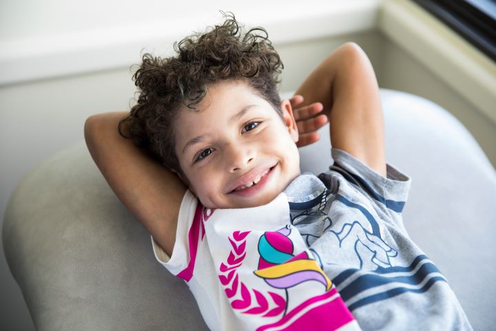 Kieesha, a girl with curly brown hair, laying on her back smiling.