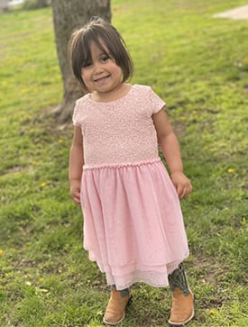 Cambree Alvarez smiling while wearing a pink dress and brown cowboy boots.