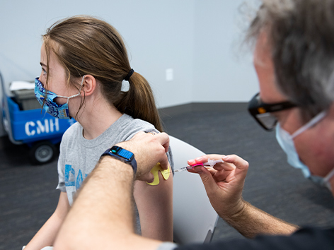 Health care provider giving a teen the COVID-19 vaccination shot.