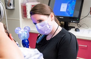 A Children's Mercy child life specialist distracting a young patient with a light-up toy.