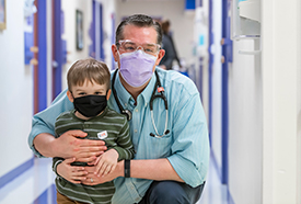 Tripp Chase with Dr. Joel Thompson inside Children's Mercy. Both are wearing face masks.