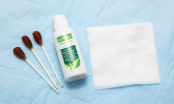 Three swabs with a bottle of soap and a white cloth.