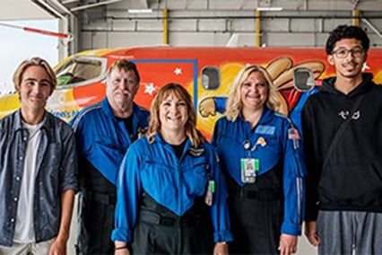 Xavier Scruggs, his teammate who performed CPR, family members and CCT staff in front of the Children's Mercy airplane in the hangar at the downtown Kansas City airport.