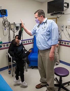 Chase Jackman and Dr. Joel Thompson giving each other a high-five inside a Children's Mercy patient room.