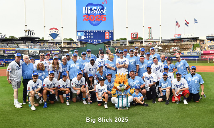 Photo of Big Slick hosts, celebrities, patient ambassadors, and Kansas City Royals mascot, Sluggger. All are wearing Royals caps and shirts while on smiling on the baseball field at Kauffman Stadium. Words read: Big Slick 2025.