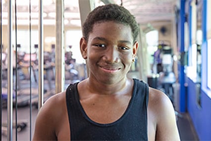An adolescent boy smiles in a sports medicine center.