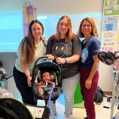 Madison holds a carseat with her son, Kingston, and stands with two NICU nurses.