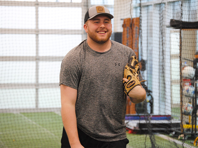 Bradley “Gage” Gulley smiling while holding a baseball glove in one hand at Village West.