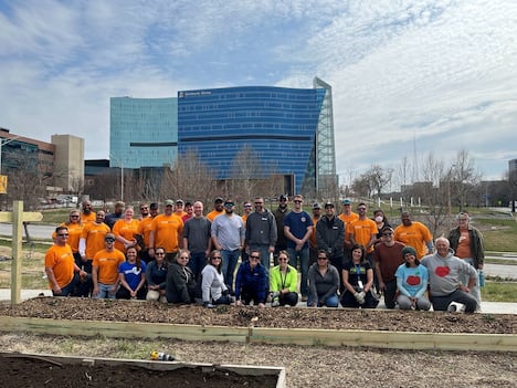 A large group of volunteers pose together after working in the Children's Mercy Community Garden.