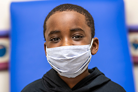 Chase Jackman wearing a face mask inside of a Children's Mercy patient room.