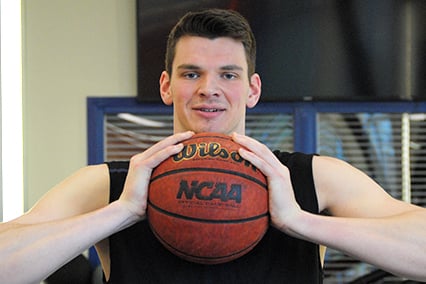 Hidde Roessink smiling and holding a Wilson basketball that also has the NCAA logo in it.